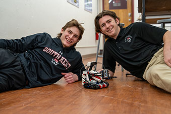 Two students posing with their robotics project. Links to Gifts by Will Two students posing with their robotics project. Links to Gifts by Will