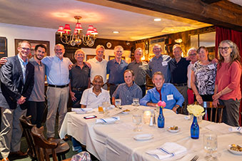 People stand around a table at a dinner. Links to Over Age 65