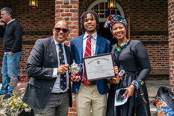 Parents proudly stand by their son as he holds his diploma. Links to Under Age 45