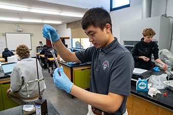 A student focusing as he fills a beaker with fluid. Links to Gifts from Retirement Plans